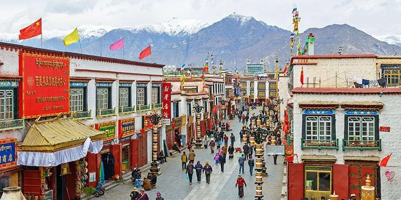 The Barkhor street in Lhasa, Tibet — pilgrims walking the circuit past incense burners and whitewashed buildings