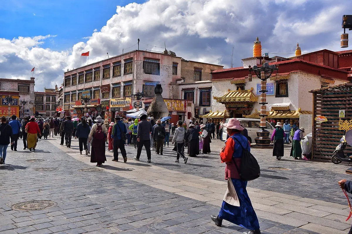 Pilgrims and prayer wheels on the Barkhor circuit in Lhasa, Tibet, whitewashed walls and market stalls along the street