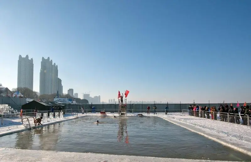 Winter swimmers in a pool cut into the frozen Songhua River in Harbin, watched from the ice