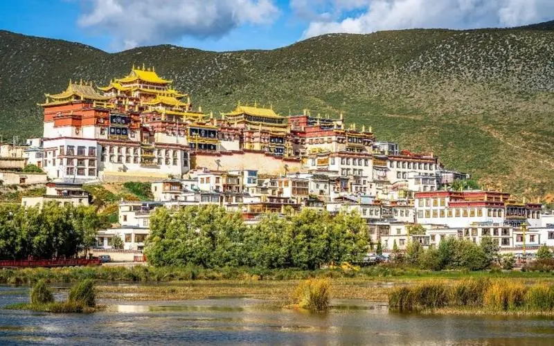Songzanlin Monastery in Shangri-La, Yunnan — golden roofs and white walls above a lake, in Tibetan style