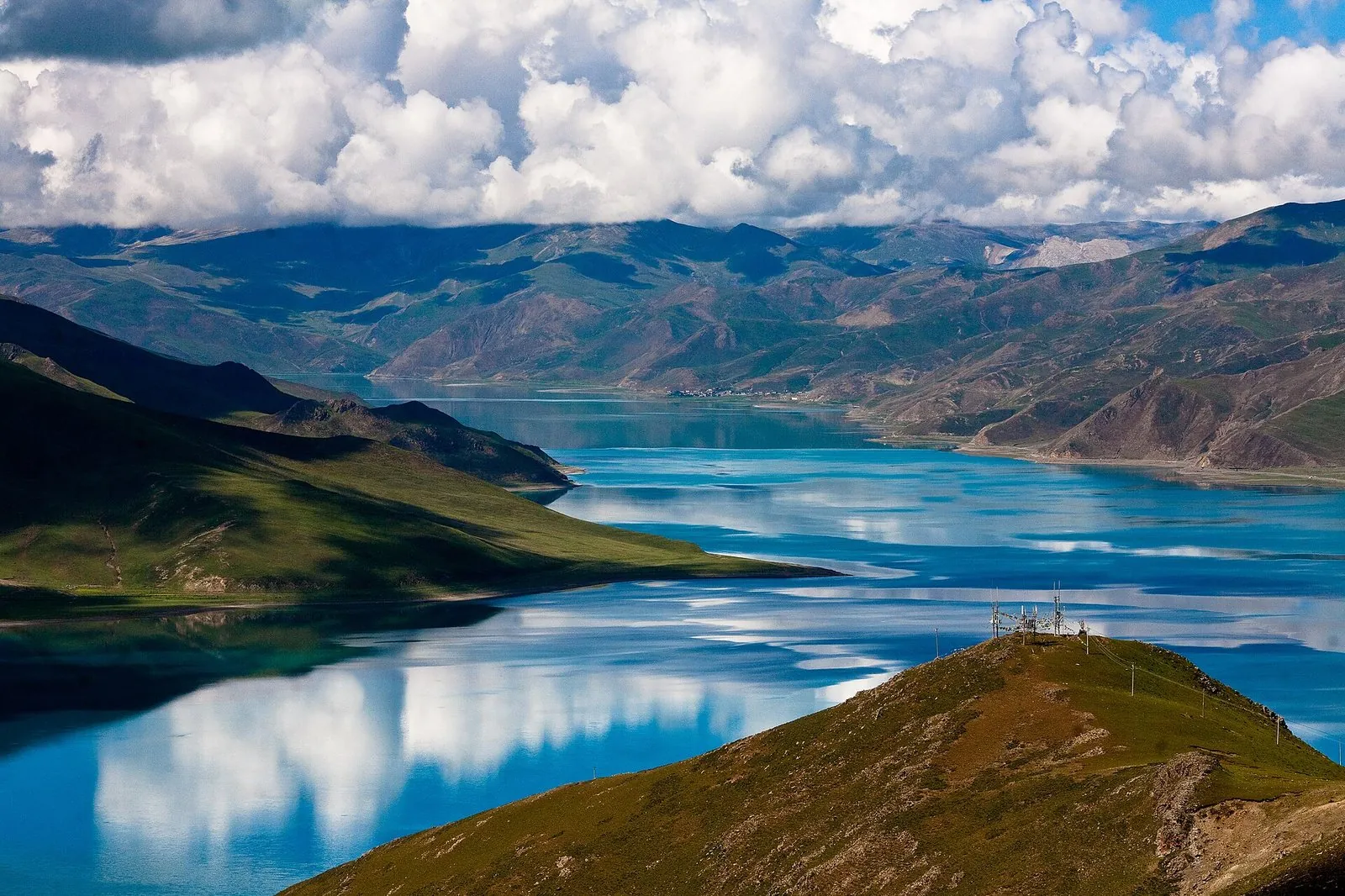 Yamdrok Lake in Tibet — a sacred turquoise lake ringed by brown hills and snow peaks, seen from the Kamba La pass on the road from Lhasa