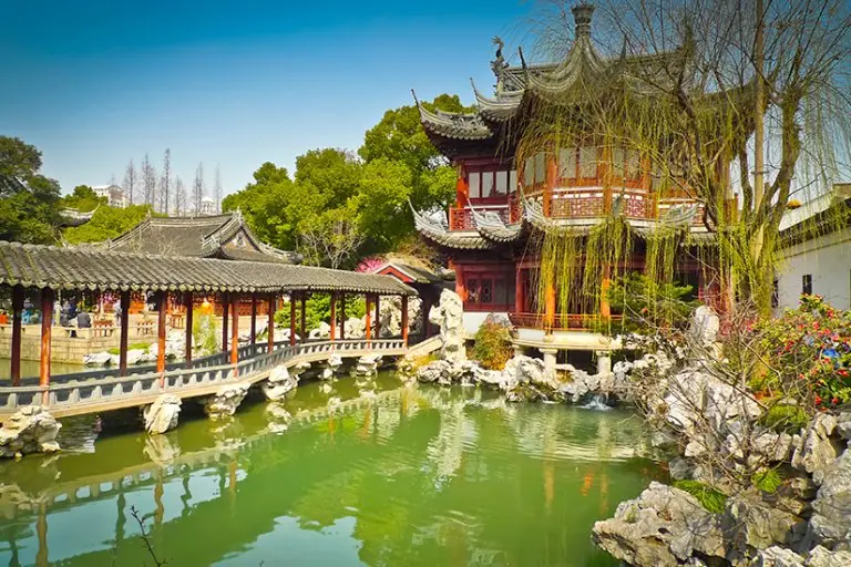 Yu Garden in Shanghai — Ming-dynasty pavilions and a covered bridge over the pond, with rockeries and willows
