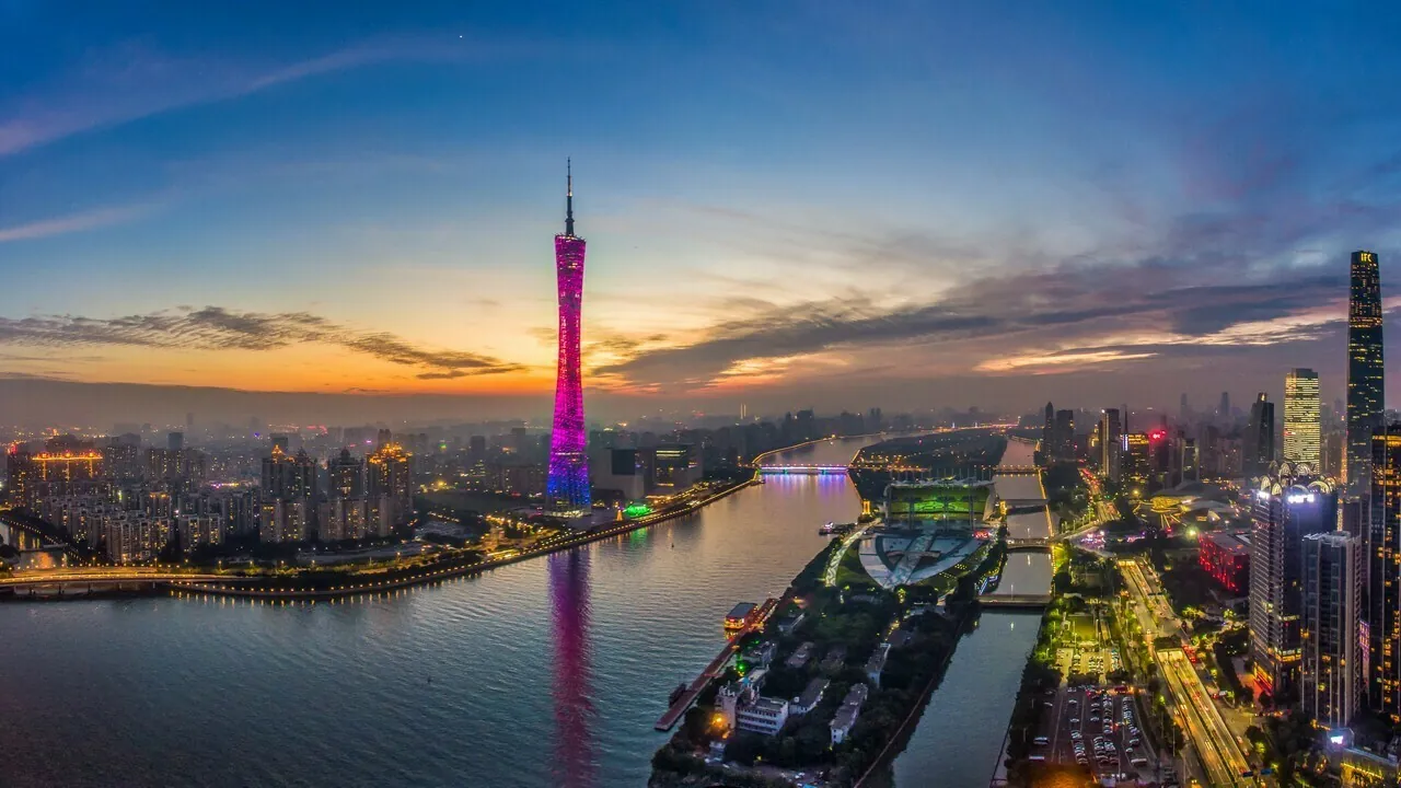 The Canton Tower lit up at dusk over the Pearl River in Guangzhou, with Haixinsha Island and the city lights coming on