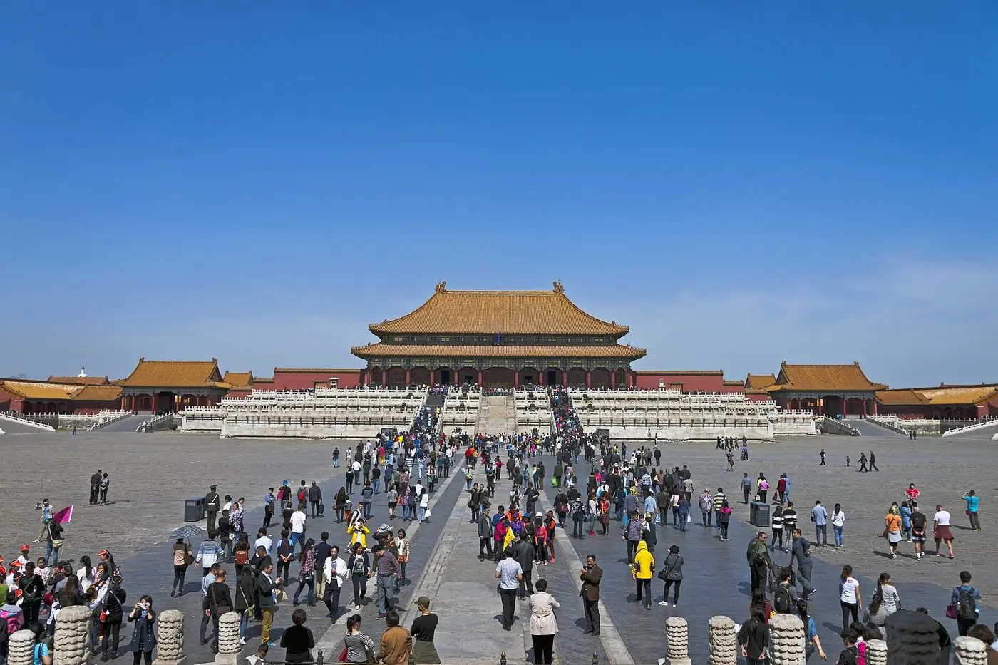 Visitors and tour guides in the courtyard of the Hall of Supreme Harmony in the Forbidden City, Beijing, on a clear day