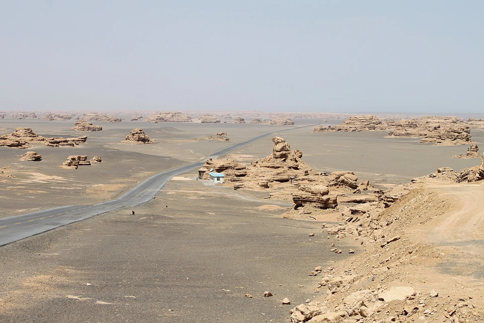 A desert highway curving through the Yardang rock formations near Dunhuang in Gansu, on the Hexi Corridor road trip